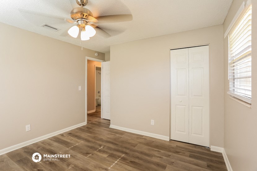 the spacious living room with a ceiling fan and a door to the bathroom
