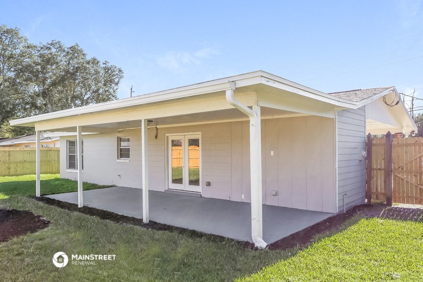 a small white house with a porch and a fence