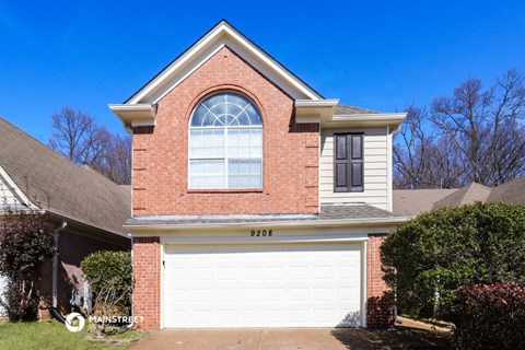a white garage door in front of a brick house
