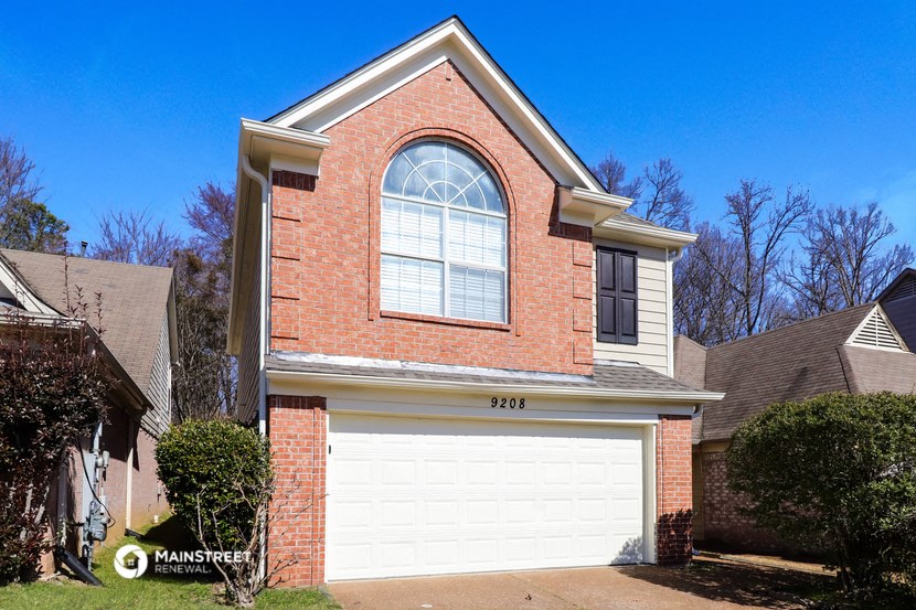 a white garage door in front of a brick house