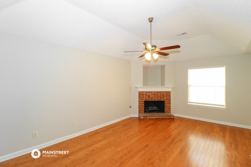 the living room with wood floors and a fireplace