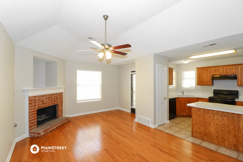 an empty living room with a brick fireplace and a ceiling fan