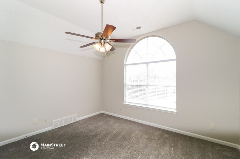 a living room with a large window and a ceiling fan