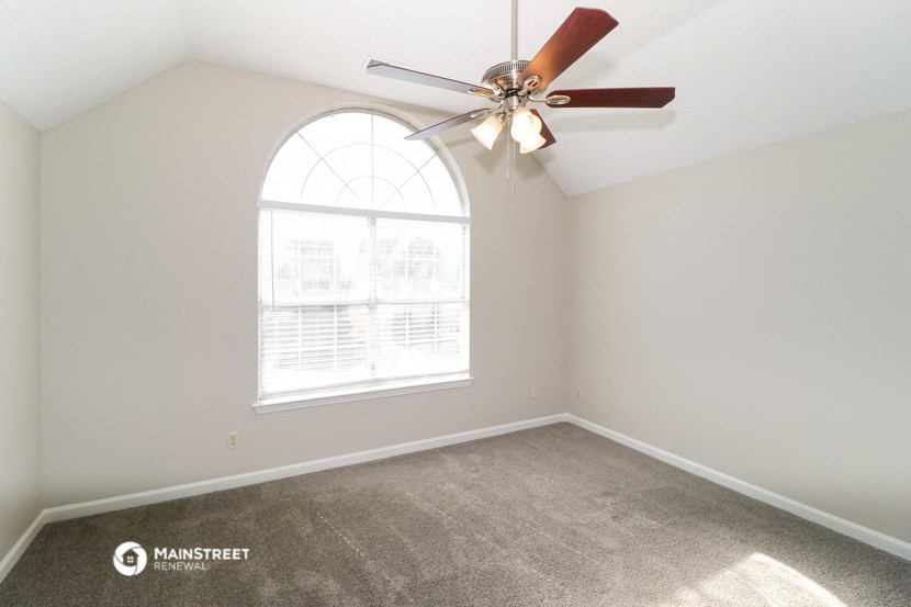 an empty room with a ceiling fan and a window