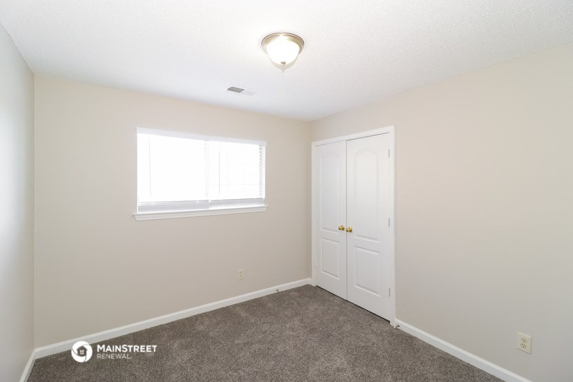 a bedroom with carpet and a white door and window
