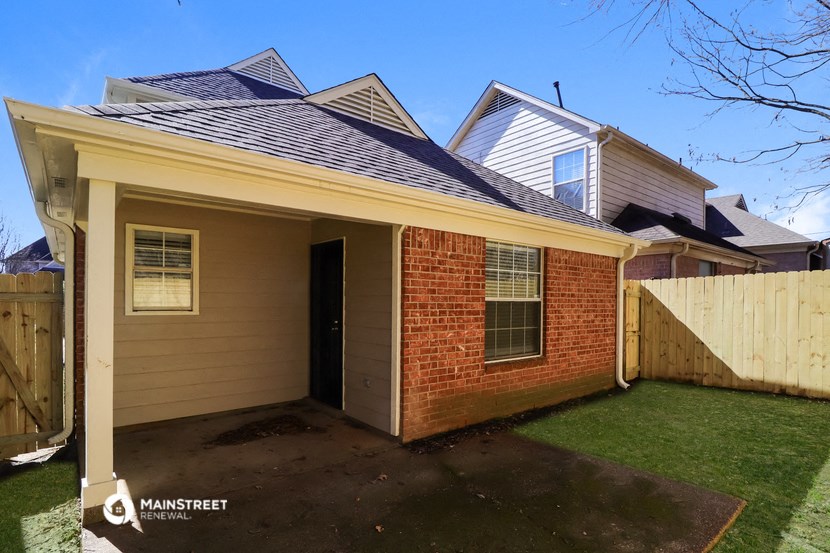 the front of a brick house with a yard and a wooden fence