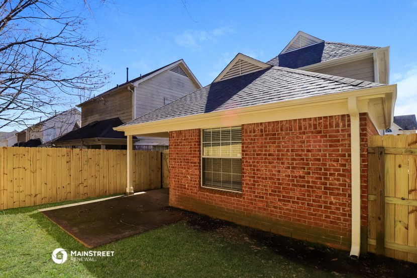 the back of a brick house with a wooden fence