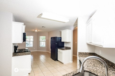 a kitchen with white cabinets and a black refrigerator