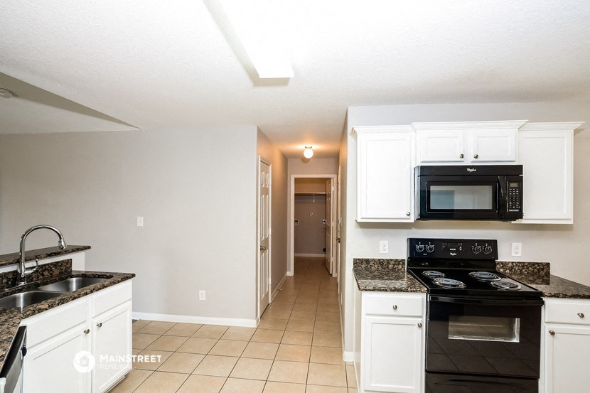 a kitchen with white cabinets and black appliances