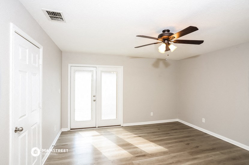 an empty living room with a ceiling fan and doors