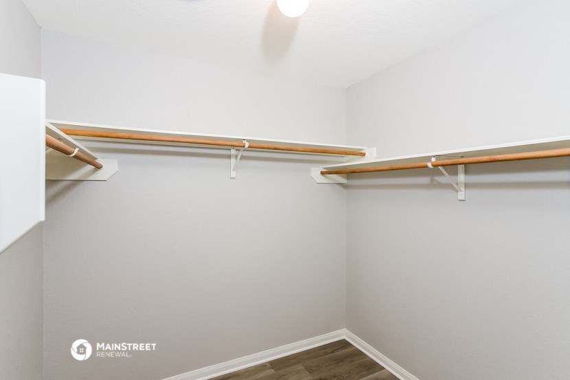 a walk in closet with shelves and a ceiling fan