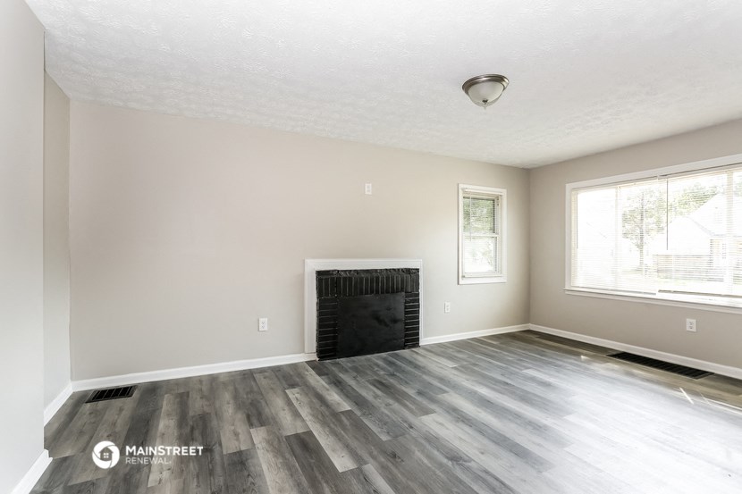the living room of a new home with wood flooring and a fireplace