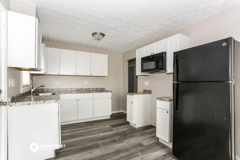 a kitchen with white cabinets and a black refrigerator