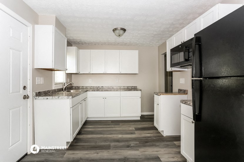 a kitchen with white cabinets and a black refrigerator