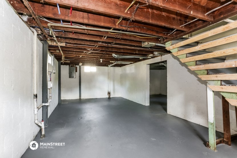 an empty basement with wooden beams on the ceiling and a concrete floor