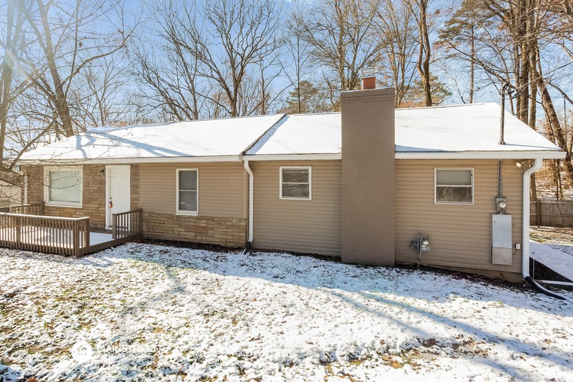a tan house with a yard covered in snow