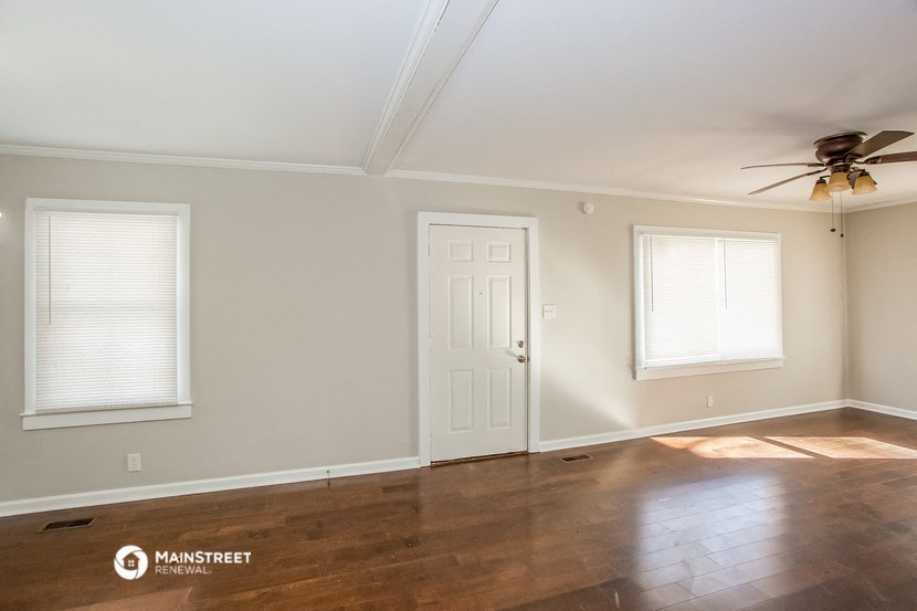 an empty living room with a ceiling fan and two windows