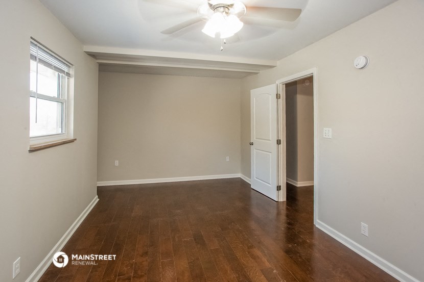 the living room of an empty house with wood flooring and a ceiling fan