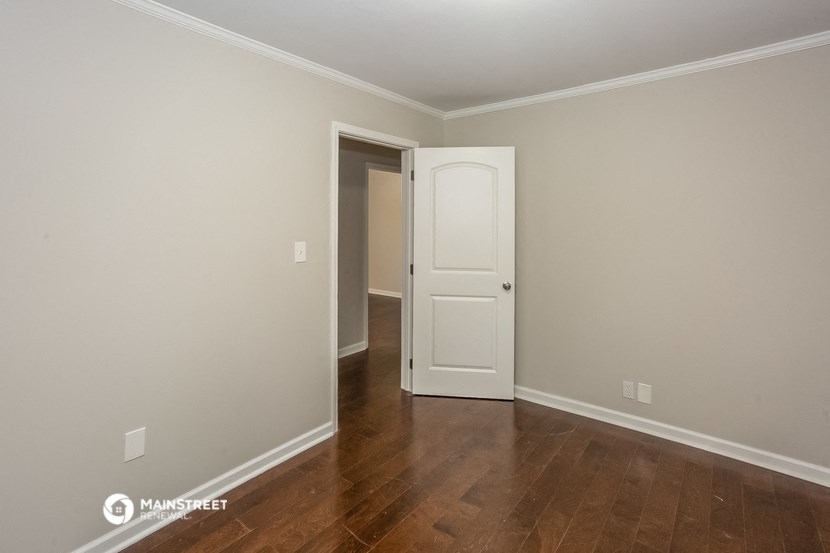 a bedroom with wood floors and a white door