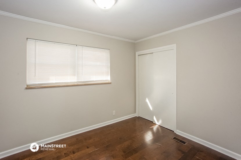 a bedroom with wood flooring and a window and a closet