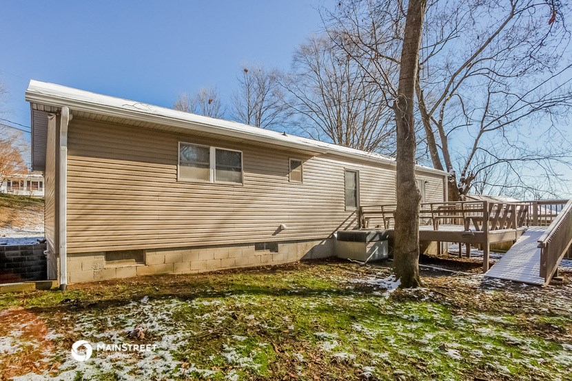 a house with a deck and a tree in front of it