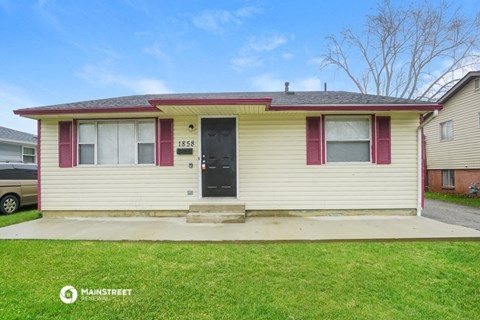 the front of a yellow house with a black door