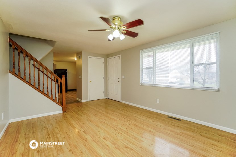 an empty living room with wood floors and a ceiling fan