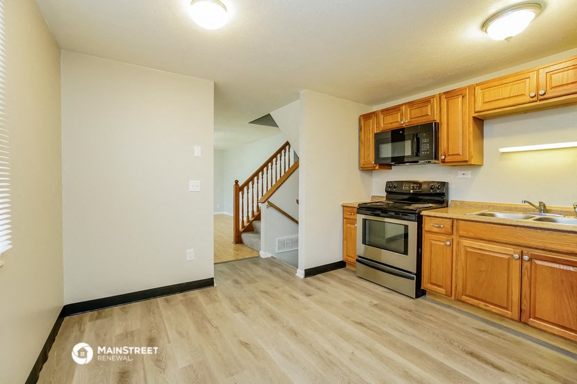 the kitchen and living room of a house with wooden cabinets and stainless steel appliances