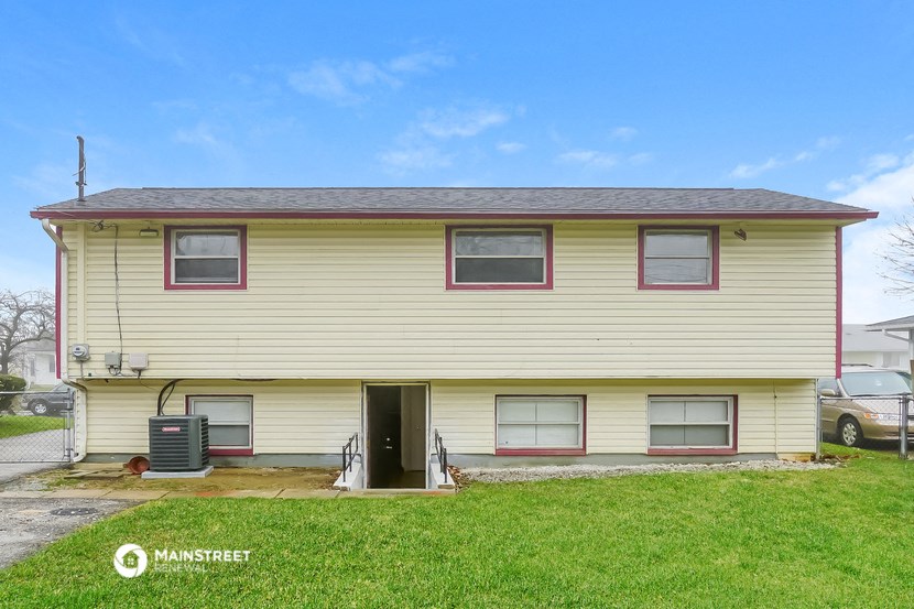 the front of a yellow house with a yard and grass