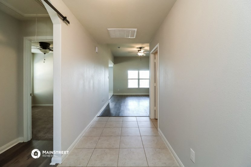 a long hallway with a white wall and a window and a ceiling fan