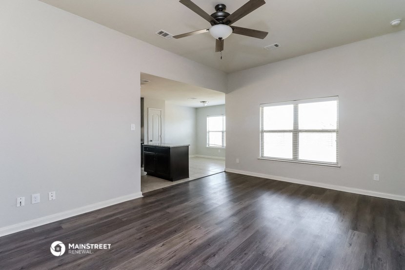 an empty living room with a ceiling fan and a window