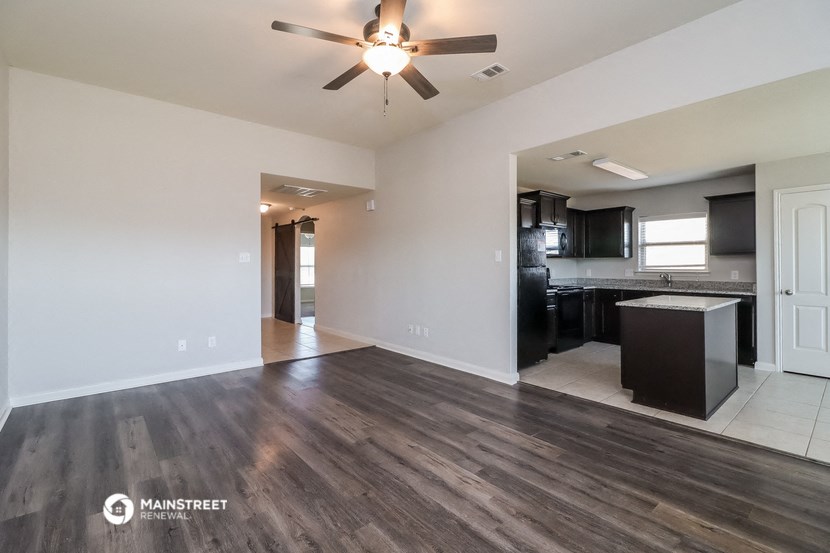 an empty living room and kitchen with a ceiling fan