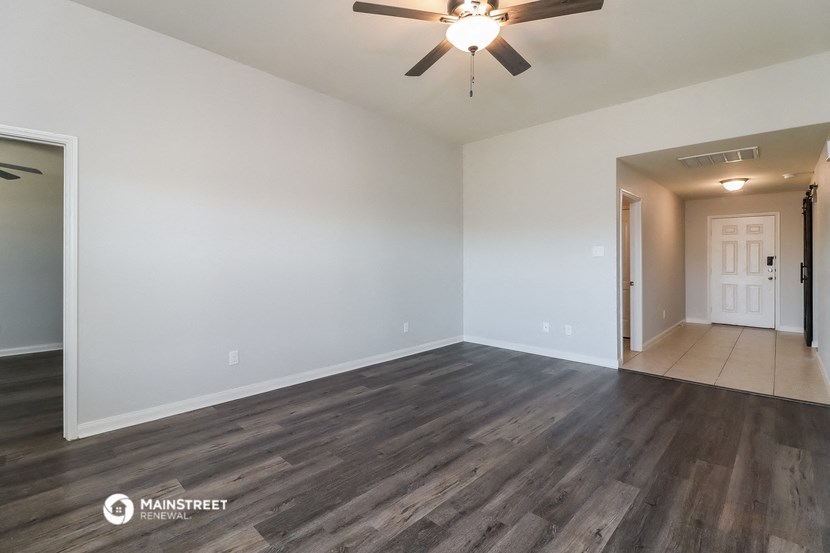 the living room of an empty house with a ceiling fan