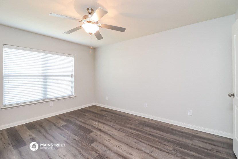 an empty bedroom with a ceiling fan and a window
