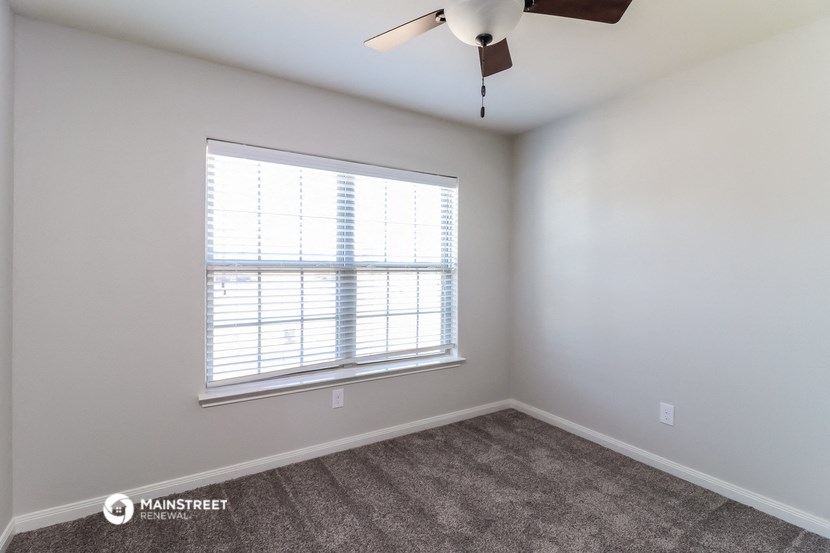 an empty room with a window and a ceiling fan