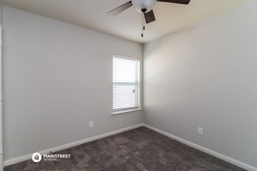an empty room with a ceiling fan and a window