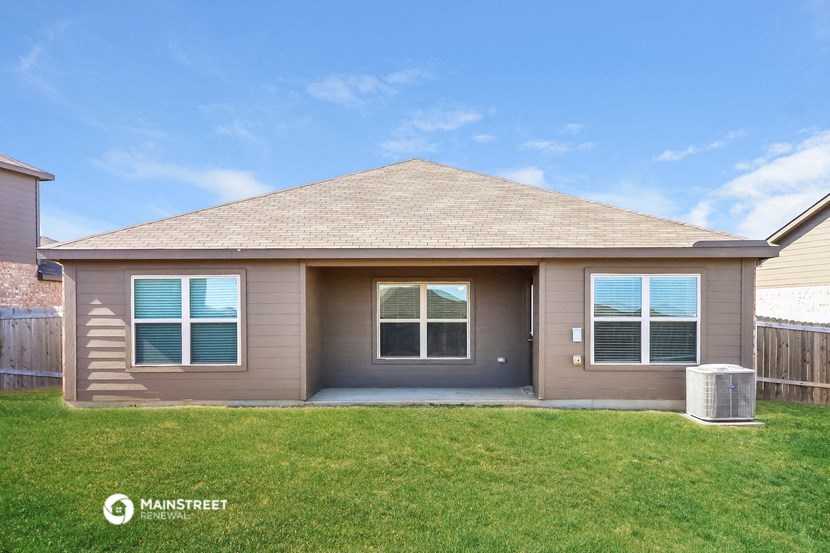 the front of a brown house with a grassy yard
