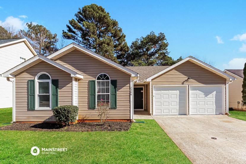 a beige house with a white garage door and a lawn
