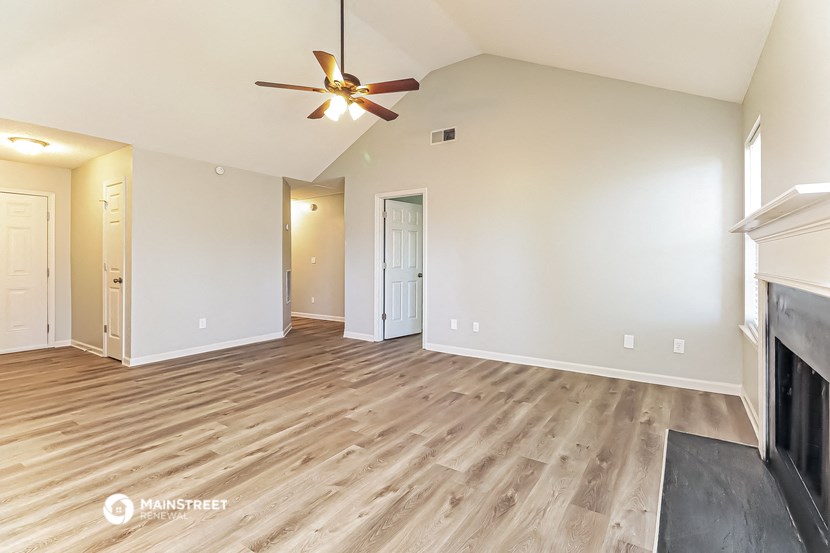 the living room with wood flooring and a ceiling fan