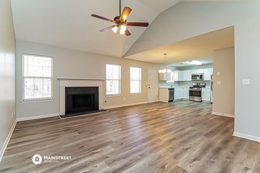 an open living room with a fireplace and a ceiling fan