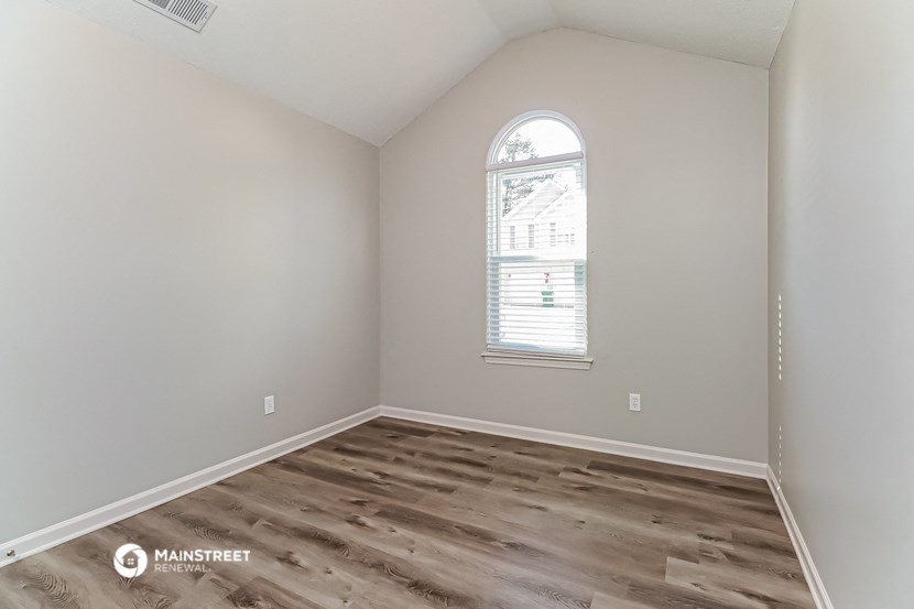 the bedroom with hardwood flooring and a large window