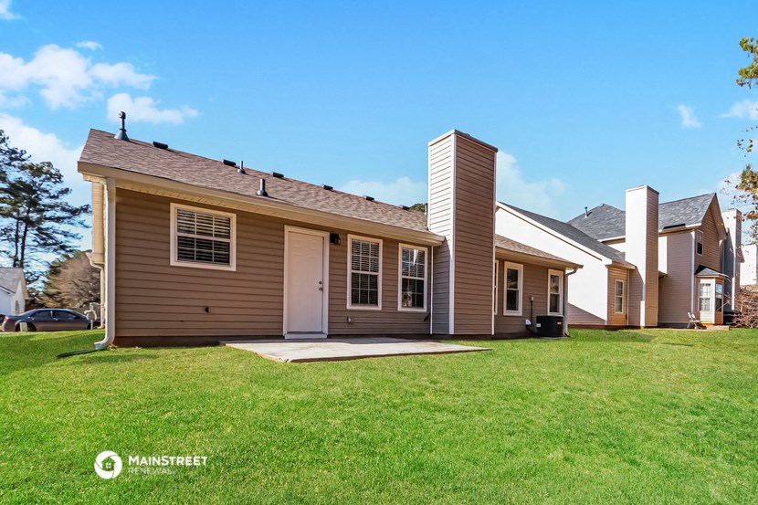 a small brown house with a yard and a garage