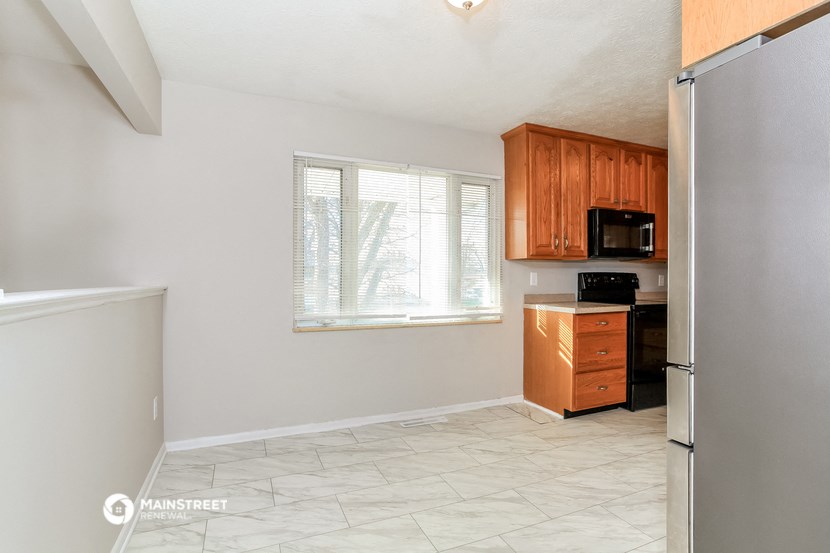 an empty kitchen with a refrigerator and a window