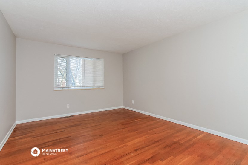 a bedroom with wood floors and a window