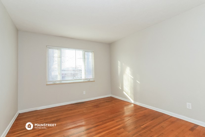a bedroom with wood flooring and a window