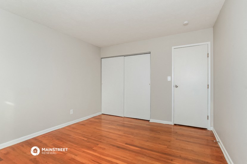 a living room with wood floors and white walls and two closets