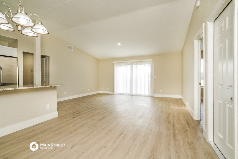 an empty living room and kitchen with wood flooring