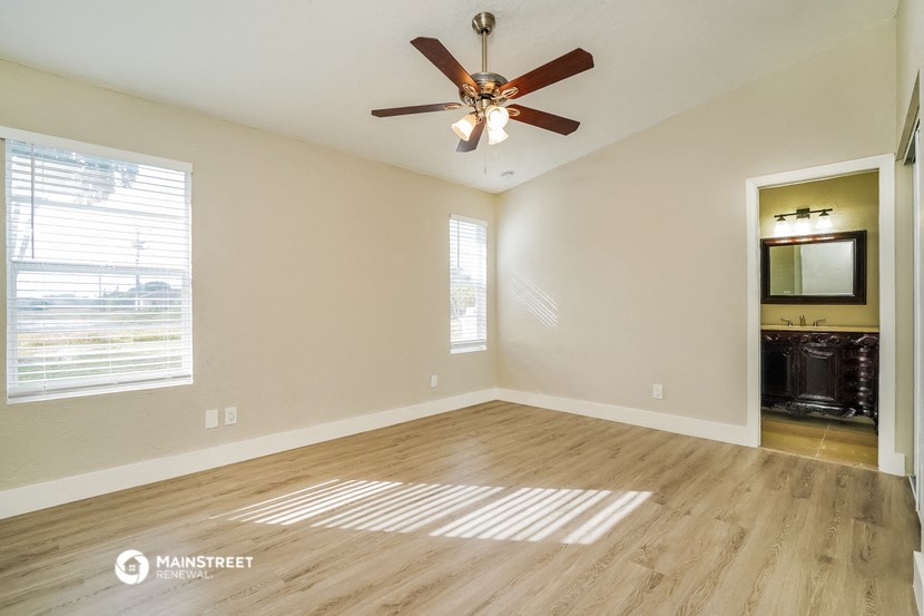 the spacious living room with hardwood floors and a ceiling fan