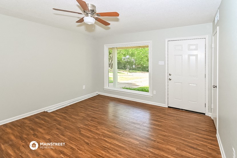 the living room of a house with wood floors and a ceiling fan