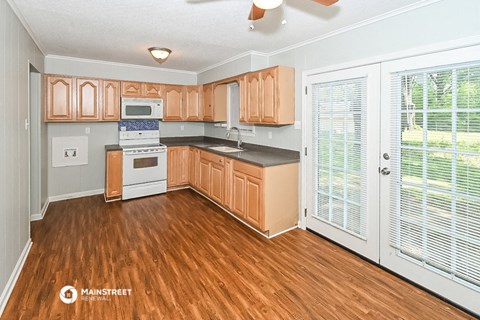 a kitchen with wood flooring and wooden cabinets and a door to a patio